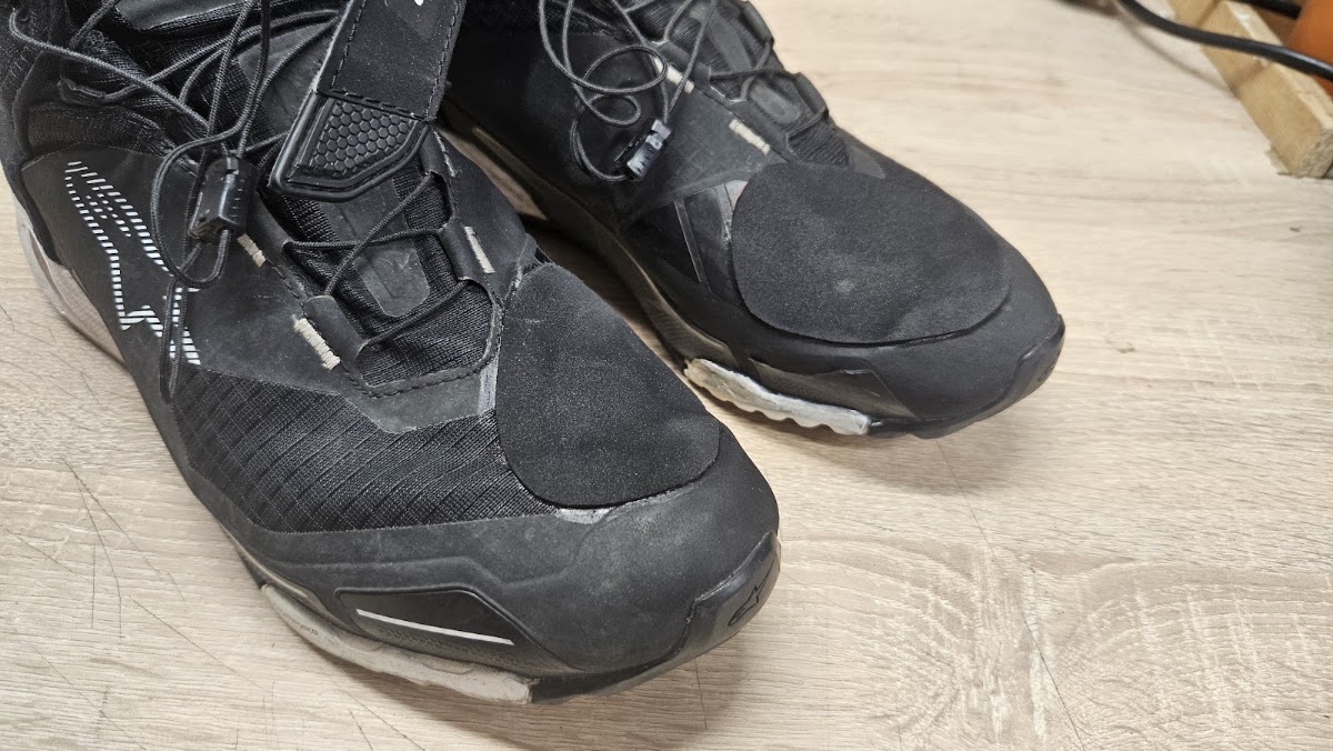 Čierna outdoorová obuv s obnovenými špičkami na pracovnom stole